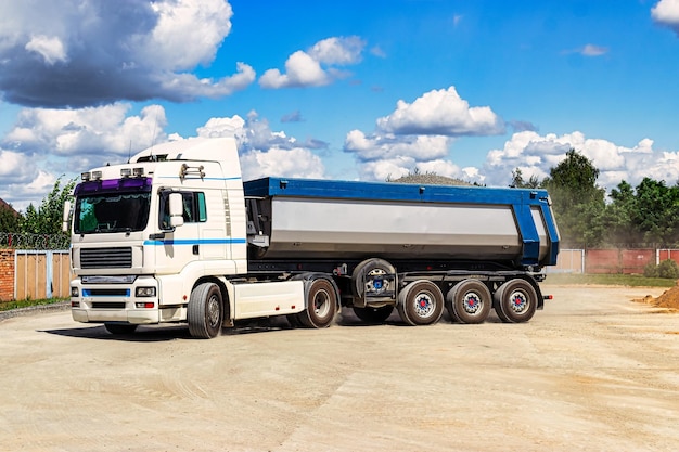 A large dump truck unloads rubble or gravel at a construction\
site car tonar for transportation of heavy bulk cargo providing the\
construction site with materials