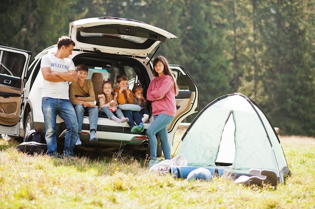 4人の子供の大家族。トランクの中の子供たち。山の中を車で旅する、雰囲気のコンセプト。アメリカの精神。