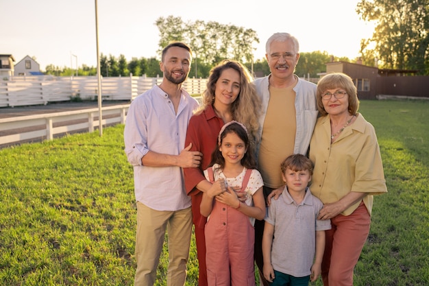 Large family of three generations standing on green lawn