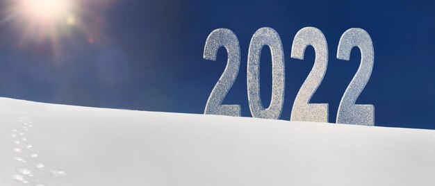 写真 明るい太陽の光の下で雪に覆われた丘の上の大きな数字2022