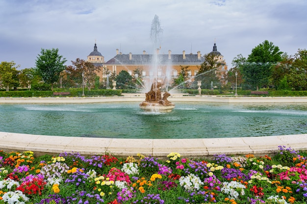 Large fountain in the gardens of the royal palace of Aranjuez with flowers of many colors