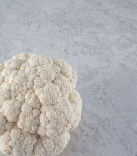 A large, fresh head of cauliflower on a light marble .  the diet.