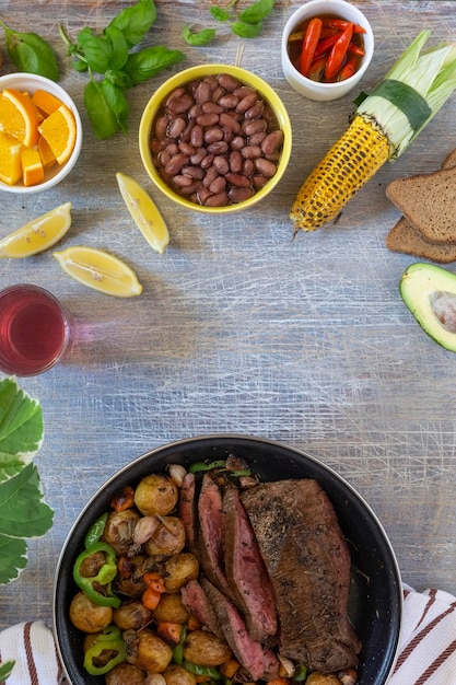 Large fried piece of ham meat in a pan with vegetables and spices American lunch fried piece of meat and potatoes beans in sauce and snacks copy space for text