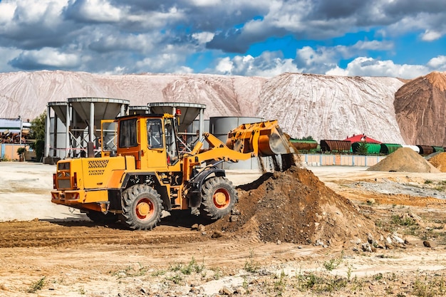 A large front loader pours sand into a pile at a construction\
site.