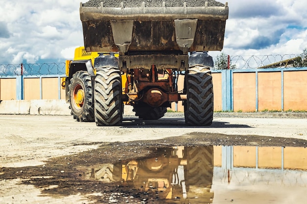 A large front loader transports crushed stone or gravel in a\
bucket at a construction site or concrete plant transportation of\
bulk materials construction equipment bulk cargo\
transportation