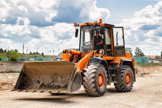 A large front loader transports crushed stone or gravel in a\
bucket at a construction site or concrete plant transportation of\
bulk materials construction equipment bulk cargo\
transportation