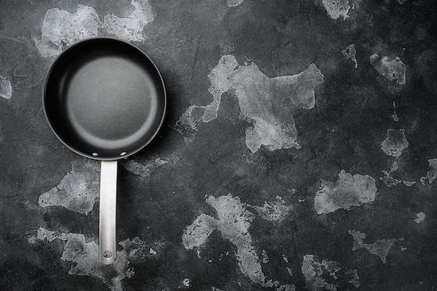 Large frying pan set with copy space for text or food with copy space for text or food, top view flat lay, on black dark stone table background