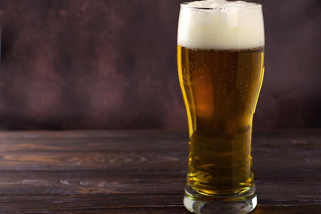 a large glass of cold light beer with foam on a dark background StPatrick s Day