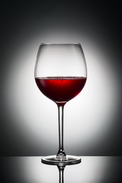 Large glass red wine shape of dark from grapes alcoholic beverage on luminous background 