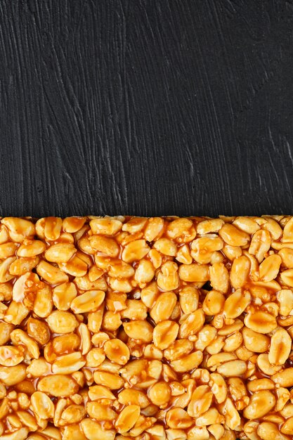 Foto una grande piastrella dorata di arachidi, una barra in una melassa dolce. kozinaki utili e gustosi dolci d'oriente