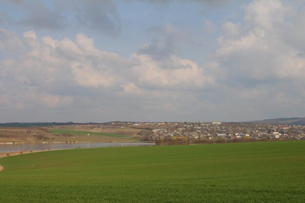 A large green field with a town in the distance