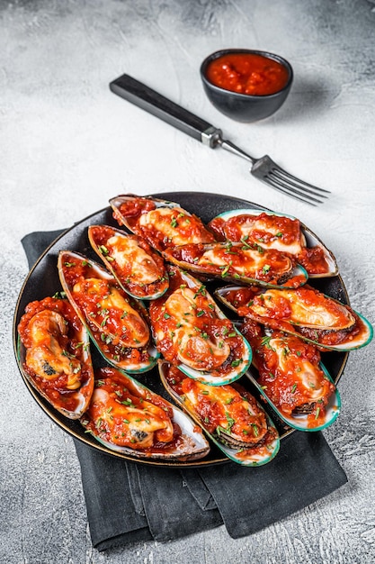 Large green mussels cooked in tomato sauce with garlic parsley and lemon White background Top view