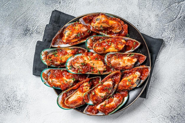 Large green mussels cooked in tomato sauce with garlic parsley and lemon White background Top view