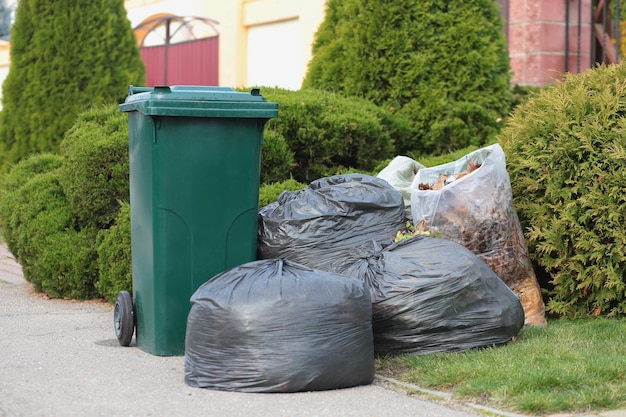 A large green plastic trash can in front of a modern house waste recycling concept