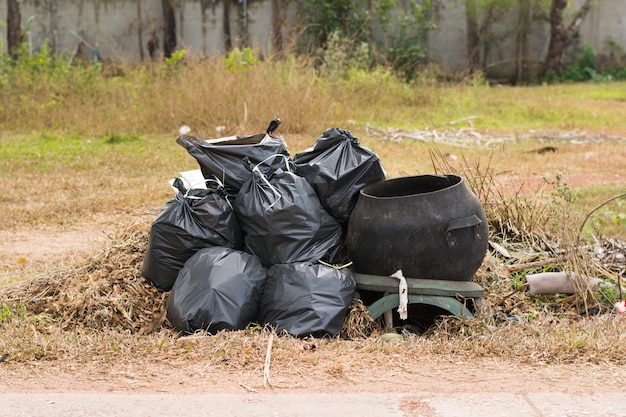 Photo large green wheelie bin for rubbish,public trash background,big pile of garbage and waiste in black bags.