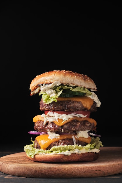 Large grilled burger with vegetables on a wooden board