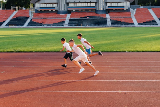 A large group of boys ' children are taught by a coach at the start before running at the stadium during sunset A healthy lifestyle