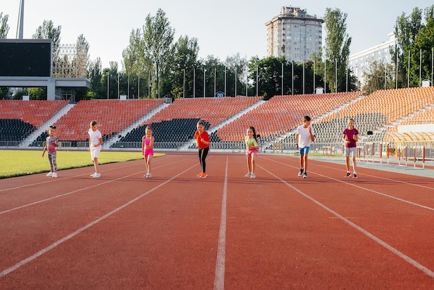 A large group of children boys and girls run and play sports at\
the stadium during sunset a healthy lifestyle