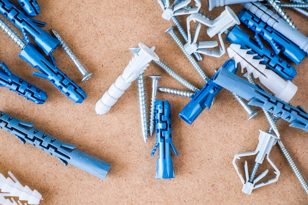 Large group of different wall plugs and screws on the brown background, high angle view