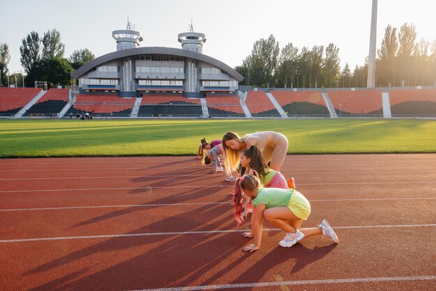 A large group of girls are taught by a coach at the start before running at the stadium during sunset A healthy lifestyle