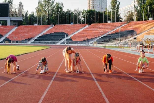 日没時にスタジアムで走る前に、最初はコーチから大勢の女の子に教えられます健康的なライフスタイル