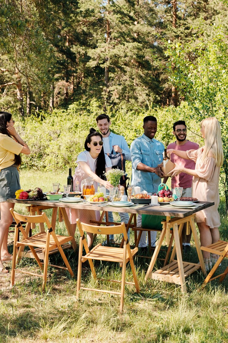 Photo large group of happy young intercultural friends unpacking bags with food products from supermarket while serving table for outdoor dinner
