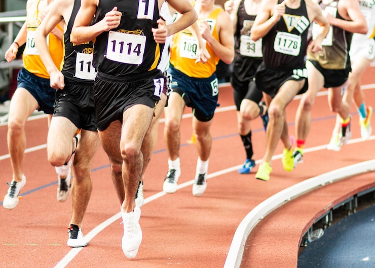Photo a large group of high school male runners racing the mile on an indoor track