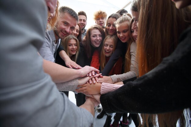 Large group of young likeminded people joining their palms