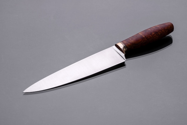 A large handmade hunting knife lying on a dark monotone background