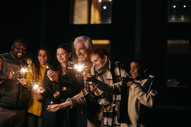 Large happy family of three generations holding sparkling bengal lights