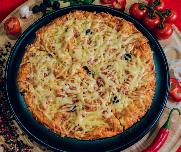 Large hot pizza on the black plate.