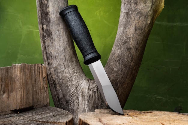 검은색 손잡이가 있는 대형 사냥용 칼 Bushcraft용 스테인레스 칼 수직 위치의 칼 나무 배경에 칼