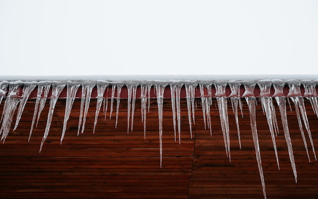 Large icicles on roof of house on cold winter day outdoors