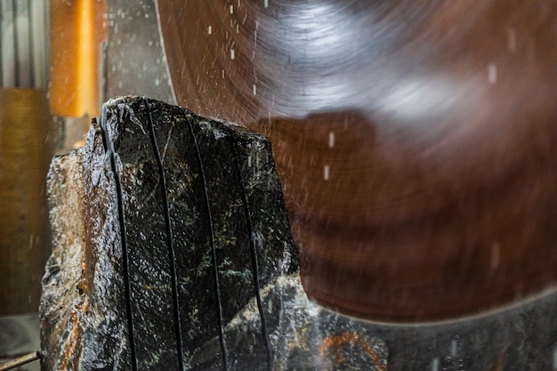 La grande macchina da taglio industriale taglia la pietra di granito grigio in lastre
