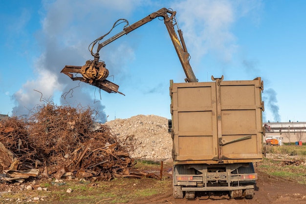 照片一个大型工业挖掘机是一堆废金属加载到一个垃圾站