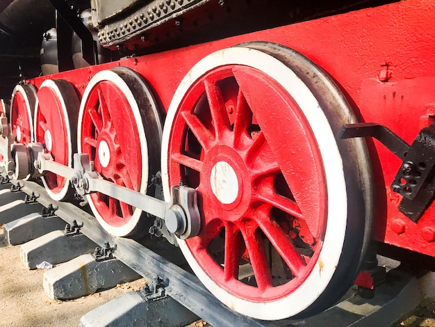 Photo large iron wheels of a red and black train standing on rails and suspension elements