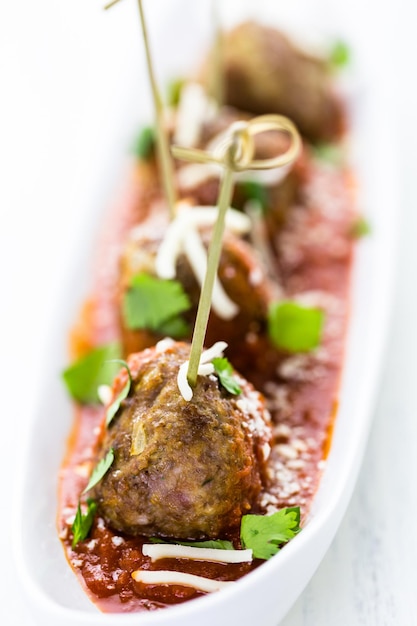 Large Italian meatballs garnished with cilantro and parmesan cheese as appetisers.