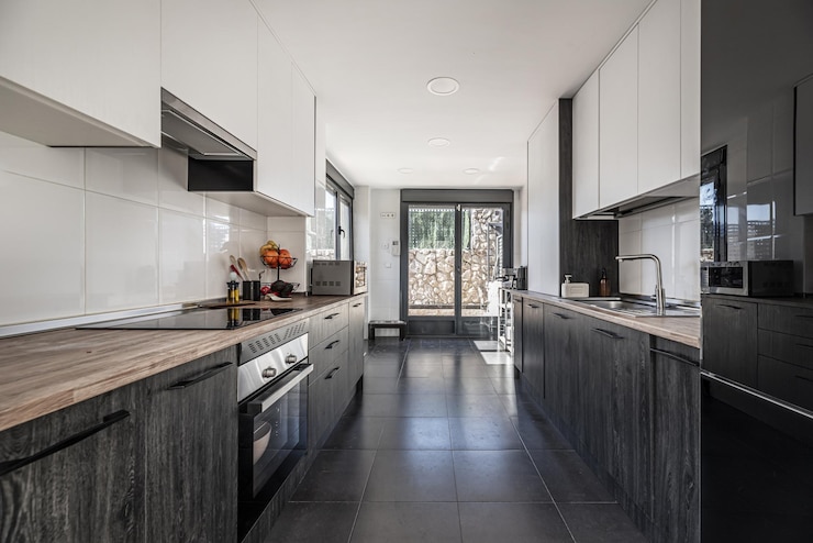 Photo large kitchen furnished with integrated black and white wooden furniture and access to a garden through a large black aluminum window