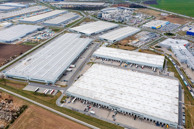 Large logistics warehouses for an online store aerial view of\
the warehouses and the roads between them many trucks waiting for\
unloading in the parking lot near the warehouses