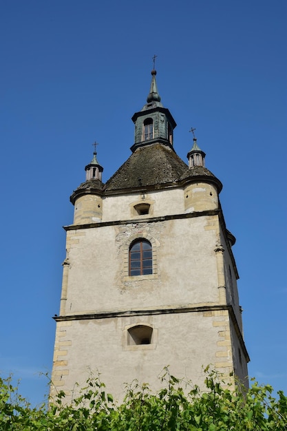 Large medieval stone tower with windows and crosses in several tiers Below green vegetation