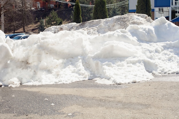 A large melting pile of snow on the dried asphalt in the spring