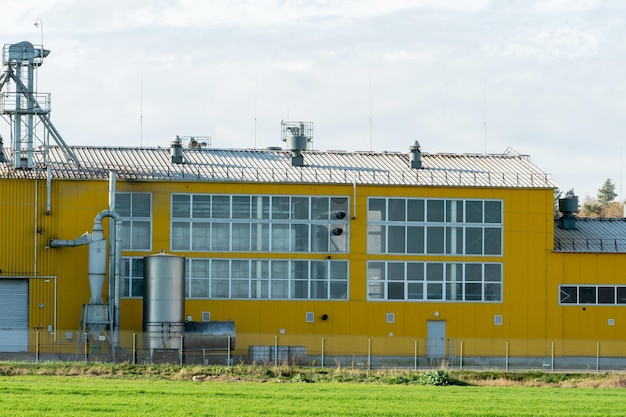 A large modern plant for the storage and processing of grain\
crops view of the granary on a sunny day large iron barrels of\
grain silver silos on agro manufacturing plant for processing and\
drying