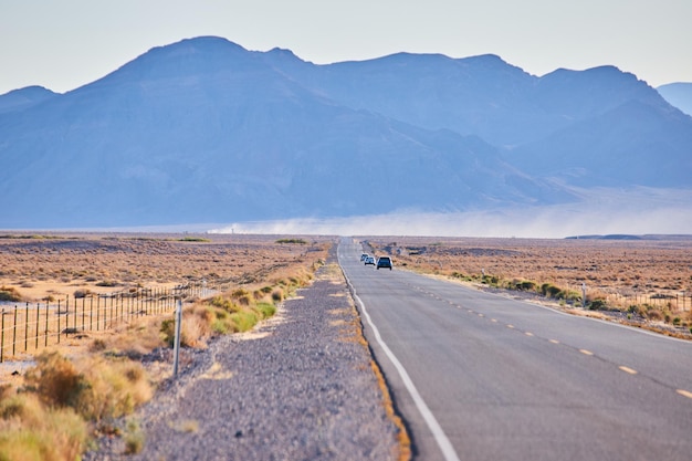 Large mountains in background as highway road leads through desert plains