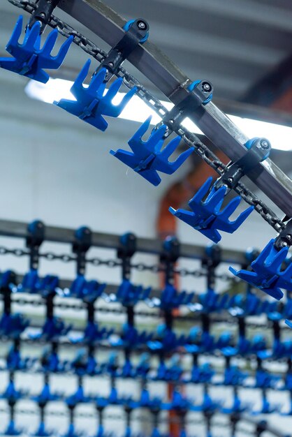 На фабрике на цепи висит большое количество синих крючков.