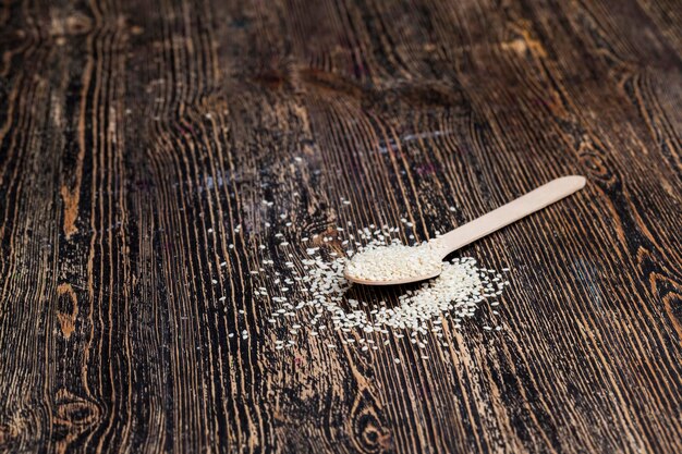 A large number of sesame seeds used in cooking and food preparation, white sesame seeds on a wooden table