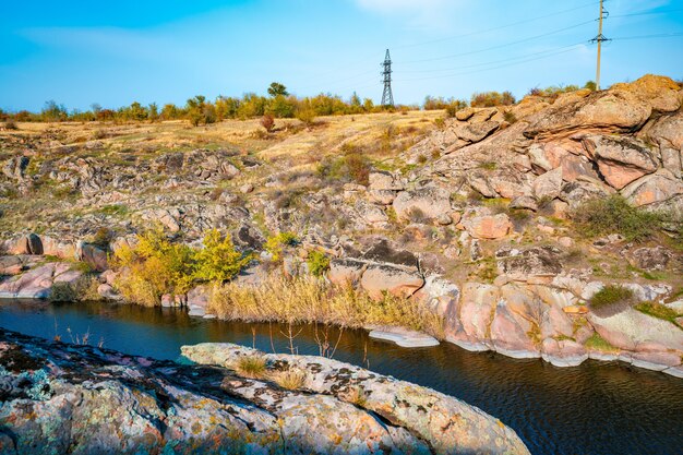 A large number of stone minerals covered with green vegetation lying above a small river in picturesque Ukraine and its beautiful nature