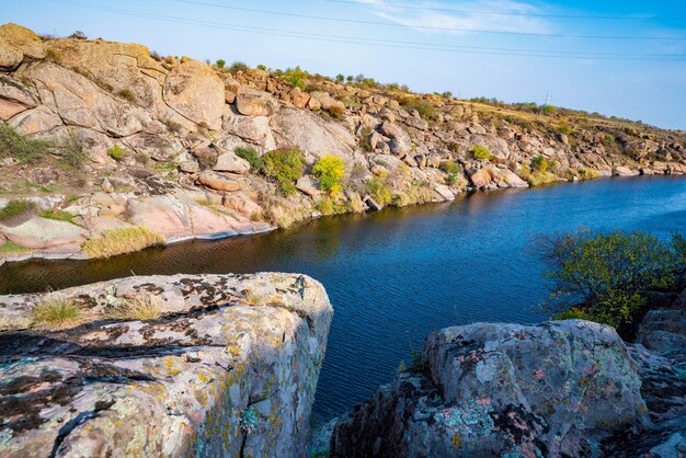 A large number of stone minerals covered with vegetation lying over a small river in picturesque Ukraine