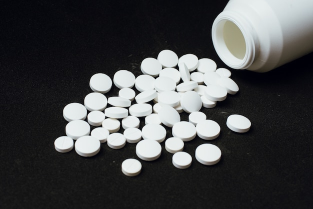 A large number of white tablets scattered from the container.