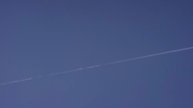 Large passenger supersonic plane flying high in clear blue sky leaving long white trail airplane