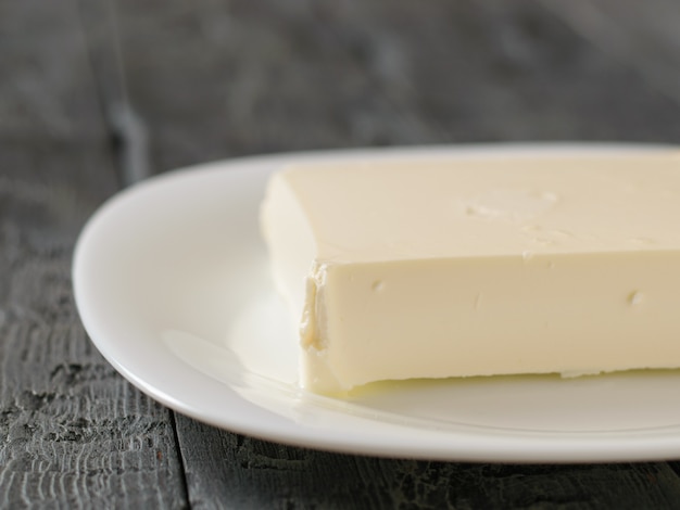 A large piece of cheese on a white plate on a black table